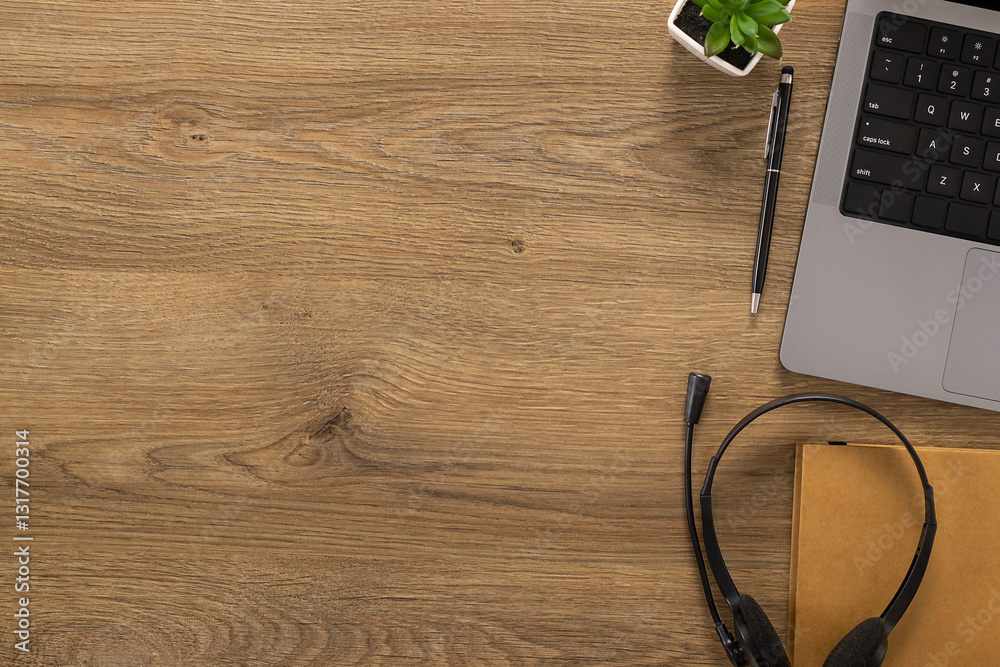 Top view of a wooden office desk with a laptop, headset, pen and notebook. A modern workspace setup for remote work, customer support, or online communication