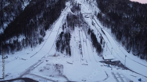 4k aerial drone panorama of Planica flying hill with many ski jumps visible in early morning.
