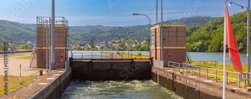 Obraz na płótnie Navigation lock on the Moselle River with water flow, control towers, and a village in the background in Germany w salonie