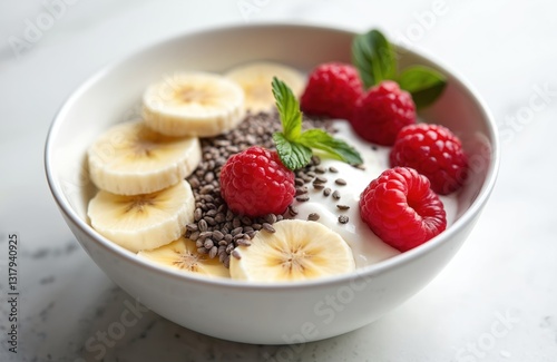 Bowl of fresh yogurt topped with banana slices, raspberries, chia seeds. Healthy breakfast inspiration with vibrant colors. Light, refreshing, simple dessert. Ideal for fitness, culinary content.