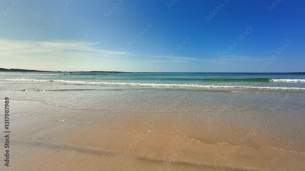 A beautiful and serene beach scene featuring gentle waves lapping at the shore under a clear blue sky A beautiful and serene beach scene featuring gentle waves lapping at the shore under a clear blue sky