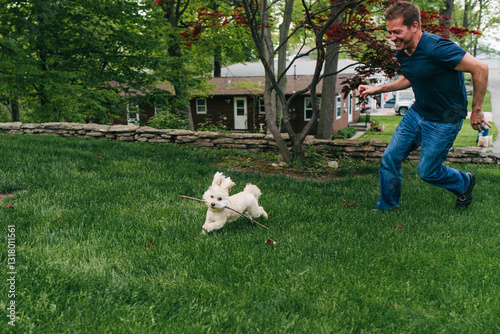 Man chasing dog in backyard photo