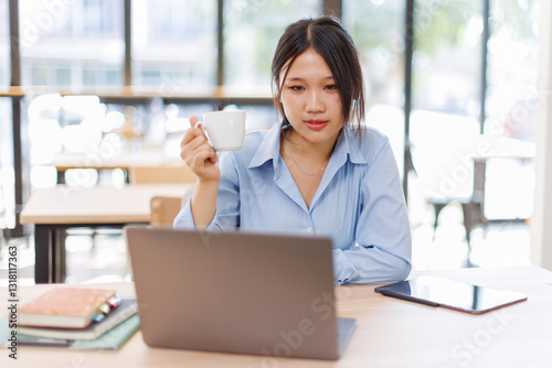 Young asian female entrepreneur working on a laptop at business meeting in a corporate workplace.
