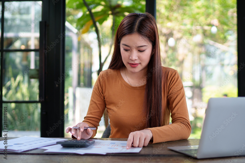 Businesswoman analyzing financial documents at a natural-themed office, focusing on charts and data for business planning.