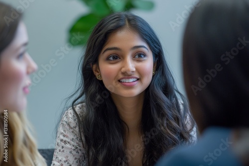 A young Indian Asian woman is having a business meeting with her team in a conference room. Her colleagues are diverse with a Caucasian brunette woman