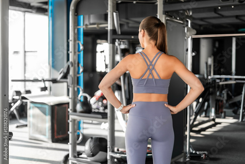 Sporty woman resting, having break after doing exercise. back view
