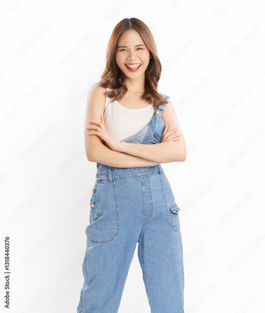 Portrait of smiling young Asian woman standing and looking at camera with arms crossed on a white background.