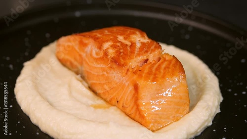 A chef places salmon on mashed potatoes. Slow motion.