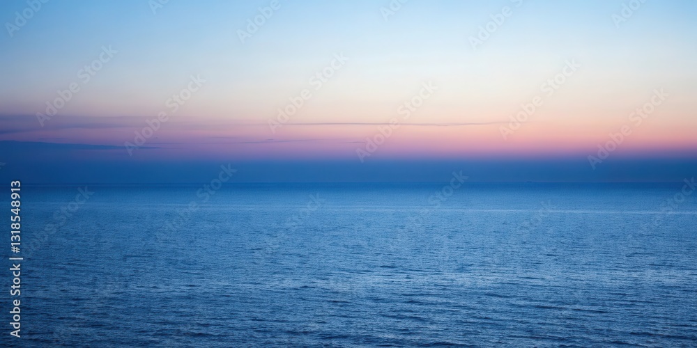 Obraz premium A serene seascape with a gentle wave pattern across the vast expanse of blue water, illuminated by a stunning sunset with a soft, pink and blue gradient in the sky.