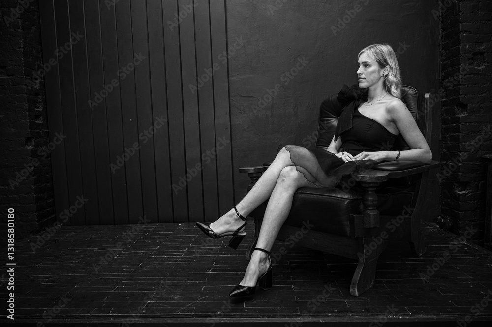 black and white photo, elegant young girl in black dress sitting in vintage leather chair, radiating confidence and elegance. Stylish portrait with dark moody background, selective focus black and white photo, elegant young girl in black dress sitting in vintage leather chair, radiating confidence and elegance. Stylish portrait with dark moody background, selective focus