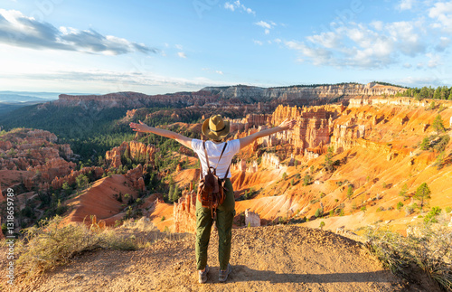Girl relaxing on vacation hiking trip. Woman standing next to Thor's Hammer hoodoo on top of  mountain looking at beautiful view. Bryce Canyon National Park, Utah, USA photo