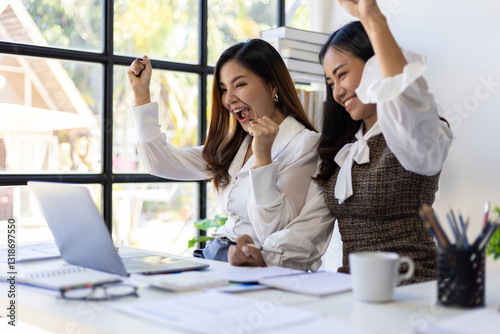 Employees and female co-workers are excited and happy about their promotions and bonuses while looking at their laptop.