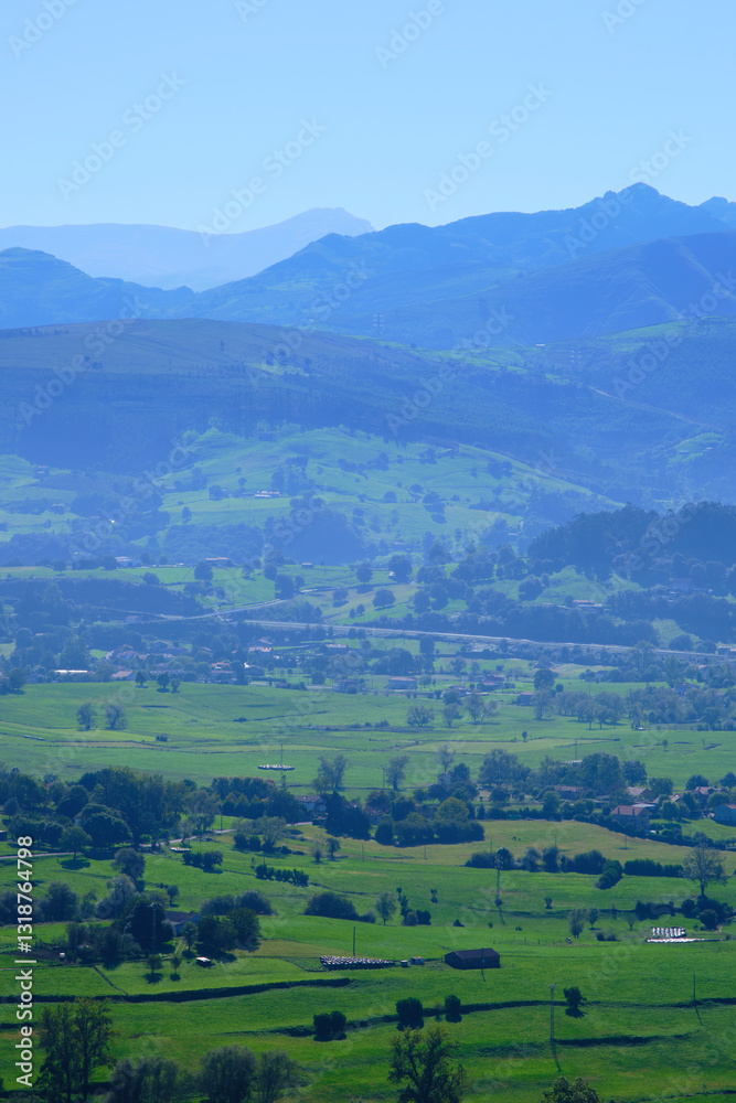 Obraz premium Breathtaking green valley surrounded by misty blue mountains in rural landscape