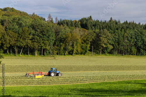 Obraz na płótnie Tractor turning hay in spring meadow, Jura, France w salonie