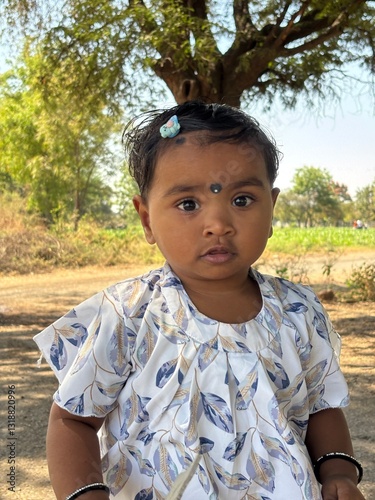 A 2-year-old Asian girl looks at the camera with a cute, confused expression, her eyes filled with curiosity.