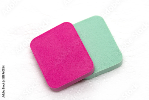 For makeup, pink and green sponges on a white background.