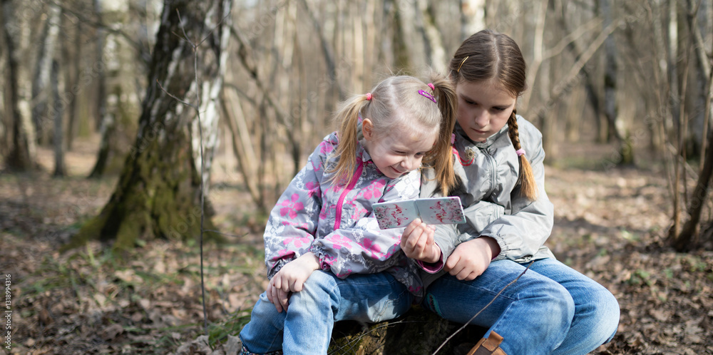 Little girls playing in the forest during the day on a beautiful autumn day. Concept of sisterhood and relationships Little girls playing in the forest during the day on a beautiful autumn day. Concept of sisterhood and relationships