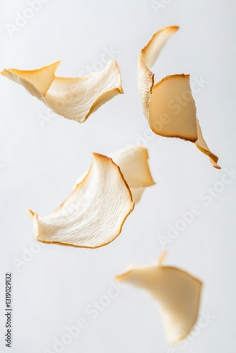 Delicate Lightly Toasted Coconut Chips Floating in Mid-Air on Soft Creamy White Background