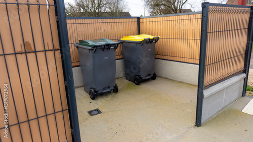 deux bacs de poubelles pour déchets ménagers et tri sélectif dans un box extérieur