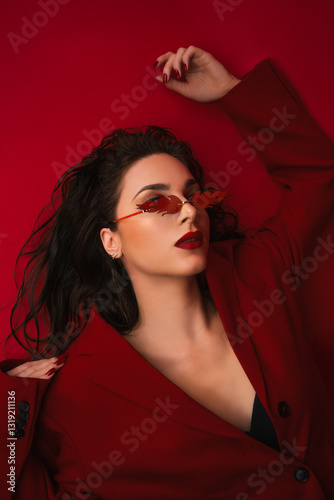 Young Woman In Red Suit With Red Lips And Sunglasses Posing On The Red Background