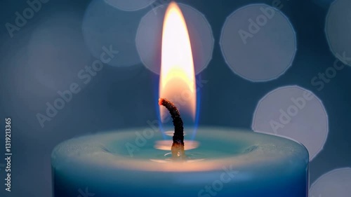 Lit blue candle with warm flame and bokeh background. Serenity and meditation concept