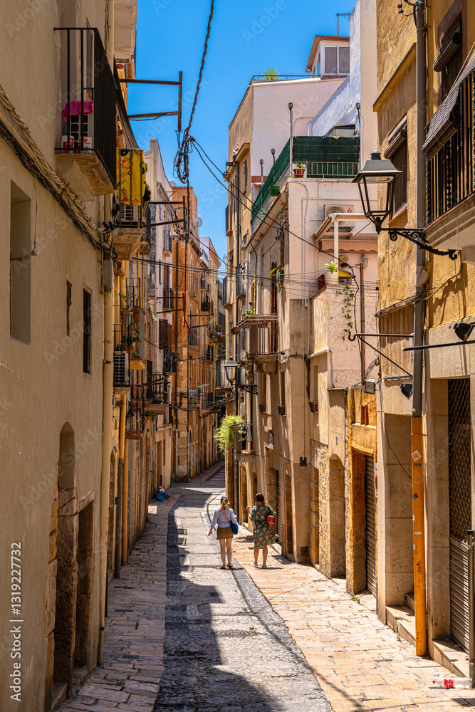 View of small alley in pedestrian area in old town of Tarragona city, on a sunny day in summer, Tarragona, Catalonia, Spain View of small alley in pedestrian area in old town of Tarragona city, on a sunny day in summer, Tarragona, Catalonia, Spain