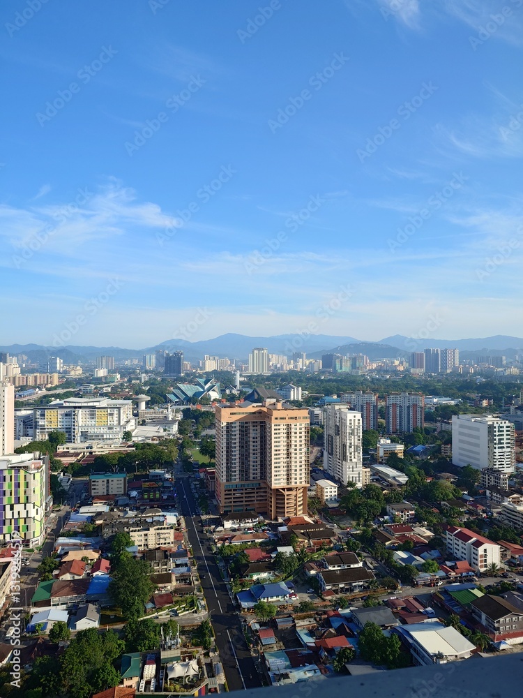 Naklejka premium A sprawling cityscape, veiled in a cloudy sky, reveals a mix of modern and traditional architecture.