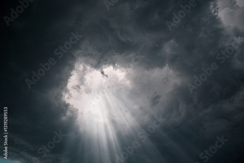 Fototapeta Naklejka Na Ścianę i Meble -  Rays of light through the hole in the dark stormy clouds in the sky.