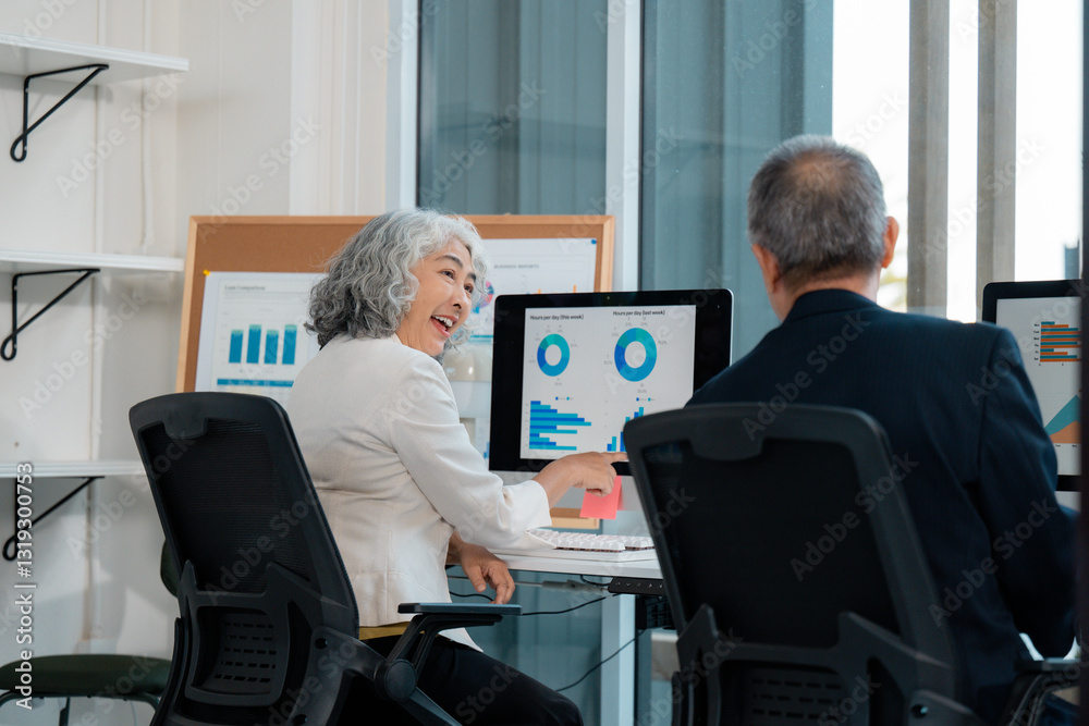 Asian senior business people analyzing financial data on computer screen in modern office Asian senior business people analyzing financial data on computer screen in modern office