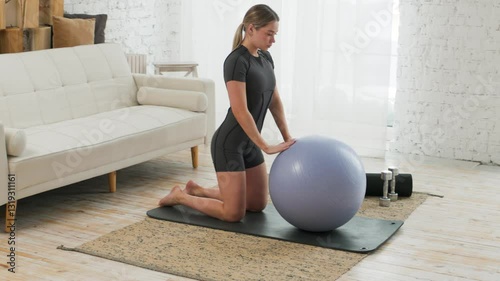Young caucasian woman doing yoga using exercise ball in bright room. The concept of a healthy lifestyle. Sports.