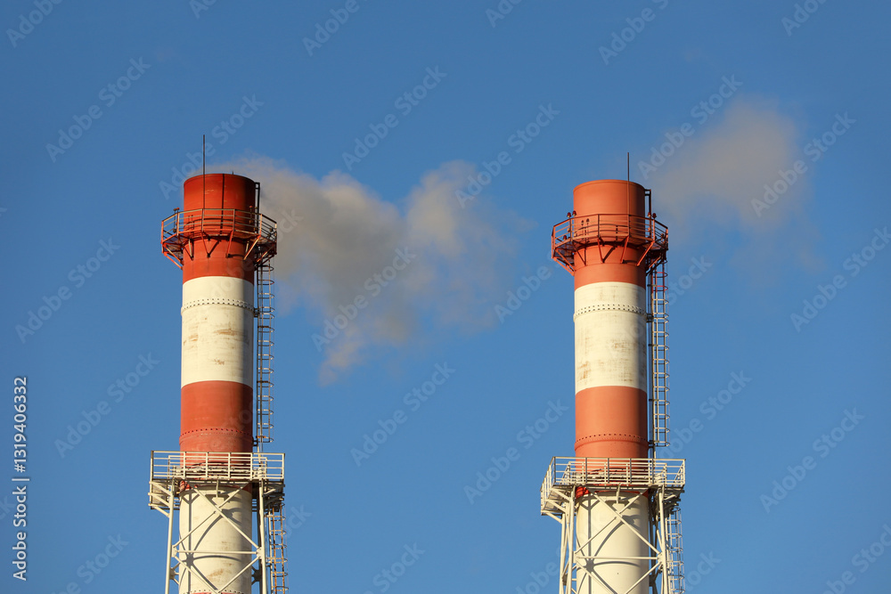 Smoking pipes on clear sky background. Concept of steam plant, air pollution, heating season or factory chimney Smoking pipes on clear sky background. Concept of steam plant, air pollution, heating season or factory chimney
