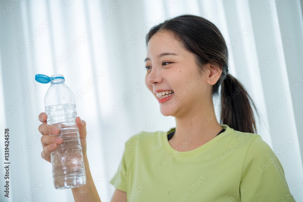Young woman enjoys refreshing water on a bright day indoors while smiling and staying hydrated Young woman enjoys refreshing water on a bright day indoors while smiling and staying hydrated