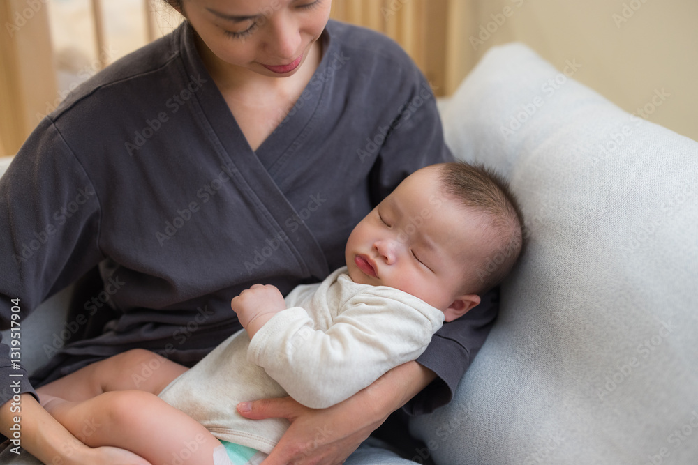 Loving mother cradling baby on cozy sofa