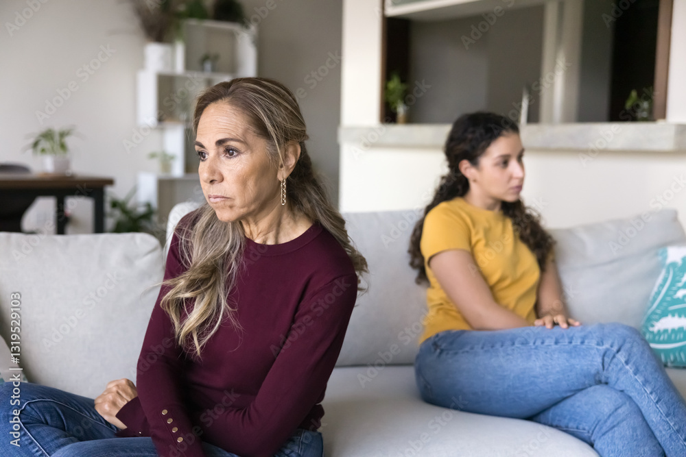 Obraz premium Mature 60s mother sitting separately on sofa with grown up 20s daughter with sad, frustrated expression, feeling unheard and invalidated, having communication issues, family conflict, misunderstanding