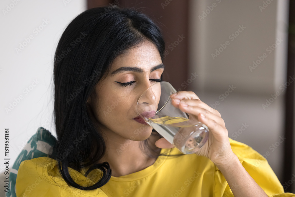 Beautiful young Indian woman drinking glass of water with her eyes closed, keep healthy lifestyle and good life habit, maintains body fluid balance, flush out toxins, relieving thirst, close up shot Beautiful young Indian woman drinking glass of water with her eyes closed, keep healthy lifestyle and good life habit, maintains body fluid balance, flush out toxins, relieving thirst, close up shot