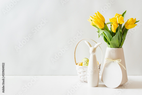 A white vase of yellow tulips and eggs on a white table