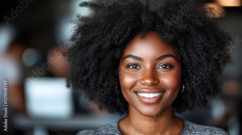 Smiling woman with curly hair in a modern setting.