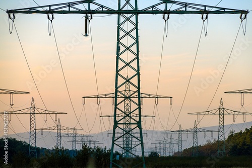 High voltage power lines over a field at sunset