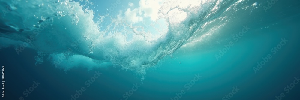 Obraz premium Beneath the surface, sunlight pierces through tranquil ocean waves, creating a serene underwater scene filled with vibrant blue hues.