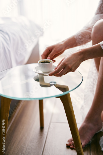 Bild auf Leinwand Bride takes a cup of coffee from a glass table while sitting in an armchair