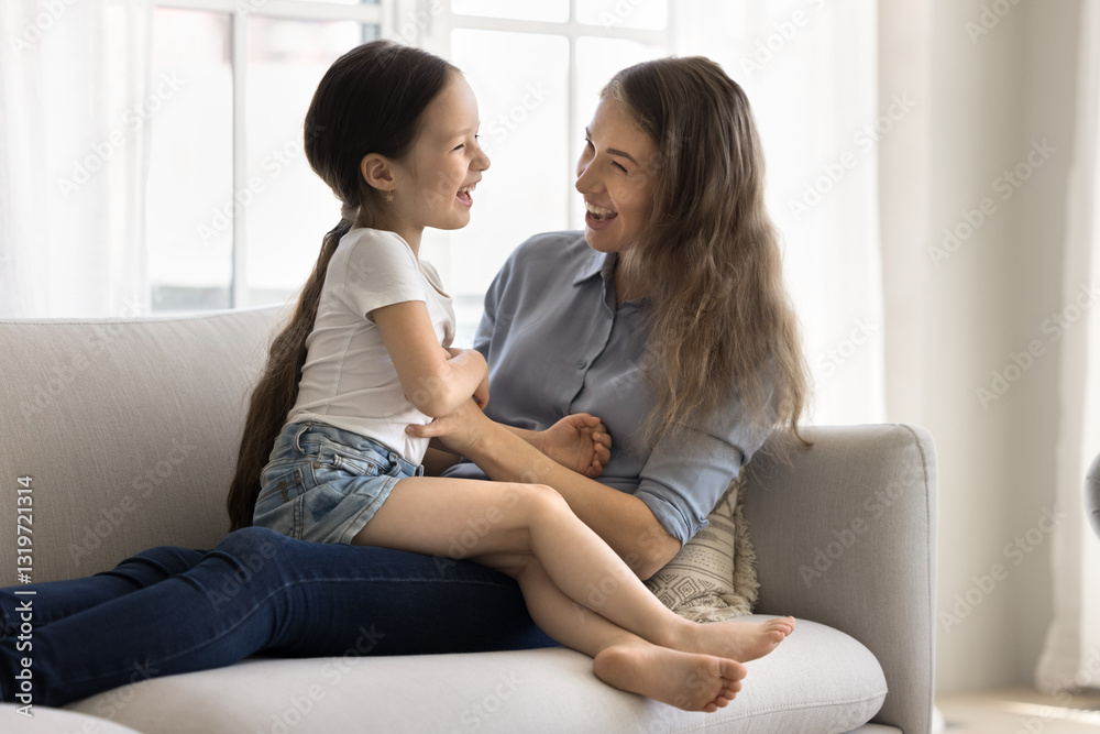 Playful family fun. Active millennial woman single mom babysitter enjoy funny activity with cute laughing small girl preschooler daughter charge tickling playing messing around on cozy couch at home Playful family fun. Active millennial woman single mom babysitter enjoy funny activity with cute laughing small girl preschooler daughter charge tickling playing messing around on cozy couch at home