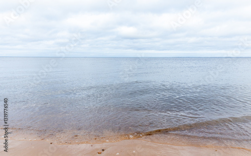 Fototapeta Naklejka Na Ścianę i Meble -  A serene sea horizon is gently meeting a sandy shore