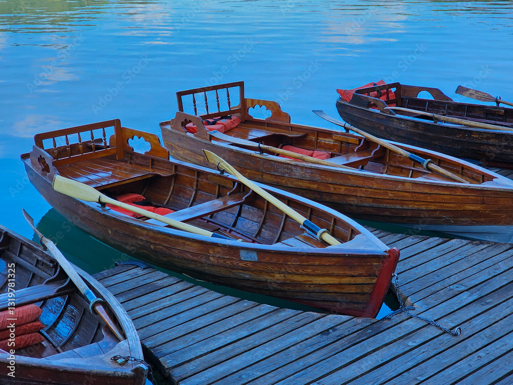 Obraz premium Wooden pletna boats floating near shoreline of lake bled, slovenia, carrying visitors toward scenic island featuring historic church destination