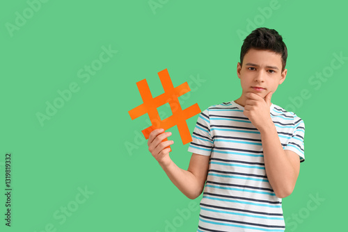 Thoughtful teenage boy with hashtag on green background