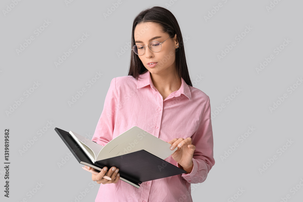 Young female writer with notebook on grey background Young female writer with notebook on grey background