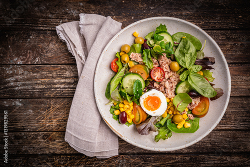 Tuna salad with tomatoes, cucumber, corn, olives , eggs and onion on wooden background, top view. High quality photo photo