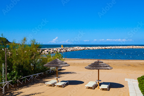 The sun-drenched Adriatic coastline: a view of the pier from the hilltop of Peschici, Apulia region, Italy, capturing the beauty of the town's beloved local beach.