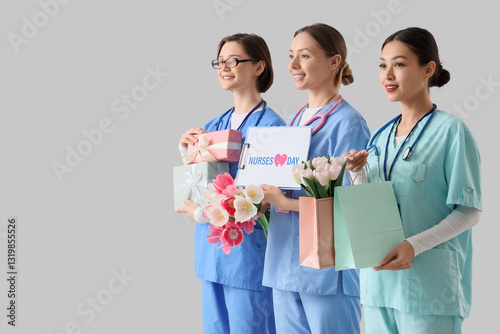 Female doctors holding clipboard with text NURSES DAY and gifts on light back...
