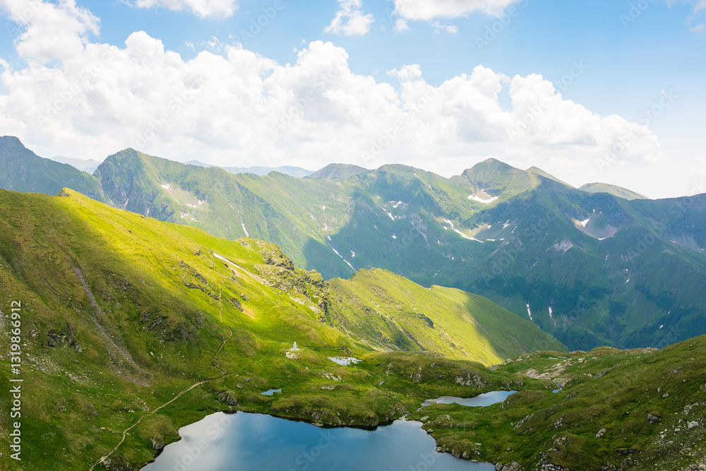 mountain landscape of romania in summer. carpathian range. beautiful outdoor scenery with alpine lake. scenic view in to the valley. travel background with blue sky and clouds. natural environment