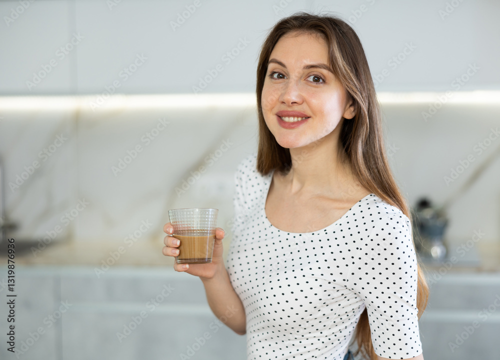 Portrait of cheerful contented woman with cup of cocoa in her hands in a modern kitchen Portrait of cheerful contented woman with cup of cocoa in her hands in a modern kitchen